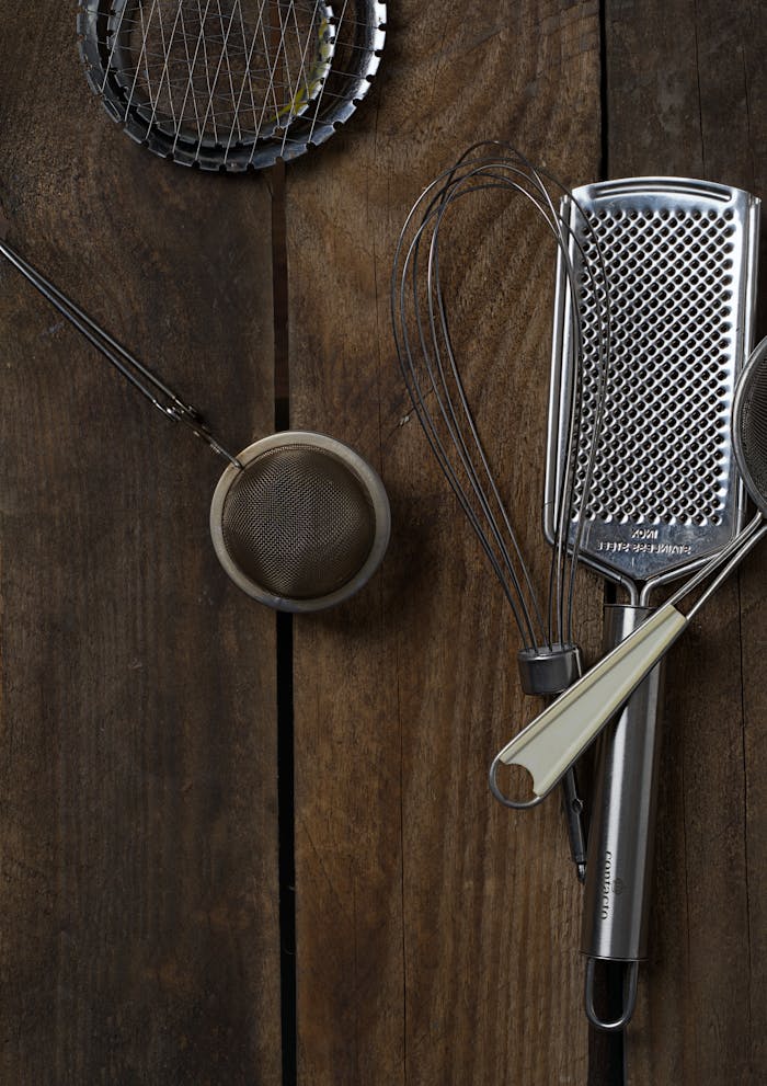 A charming flat lay of kitchen utensils on a rustic wooden surface for culinary themes.