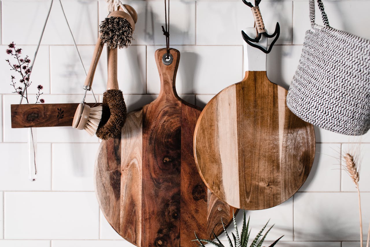 Charming wooden kitchenwares hang stylishly on a white tiled wall, perfect for rustic decor.
