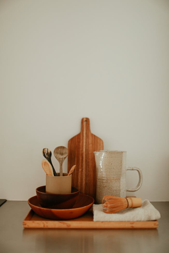 Elegant still life featuring ceramic pitcher and wooden kitchen utensils.