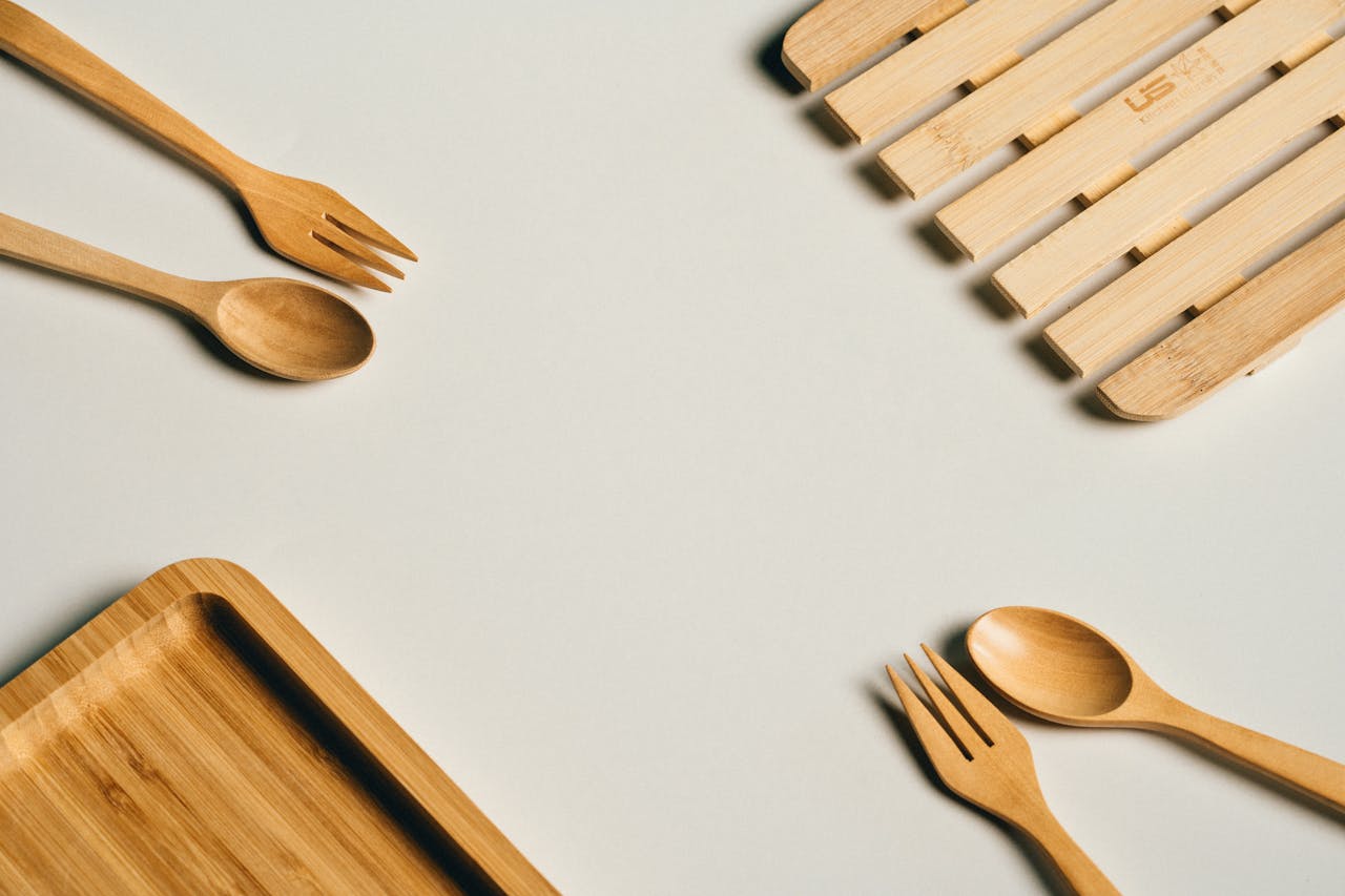 Flat lay of bamboo fork, spoon, and tray on a minimalist background.